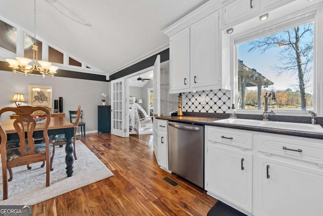 kitchen with stainless steel dishwasher, sink, pendant lighting, white cabinets, and lofted ceiling