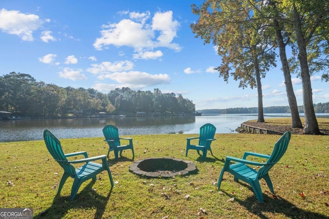 view of property's community featuring a water view, a fire pit, and a lawn