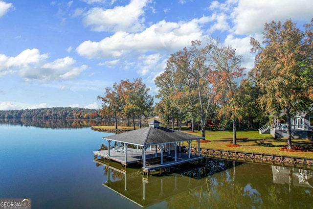 view of dock with a lawn and a water view