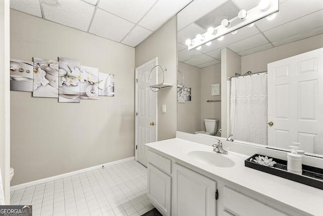 bathroom with tile patterned floors, a drop ceiling, toilet, and vanity