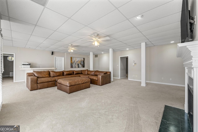 carpeted living room with ceiling fan and a paneled ceiling