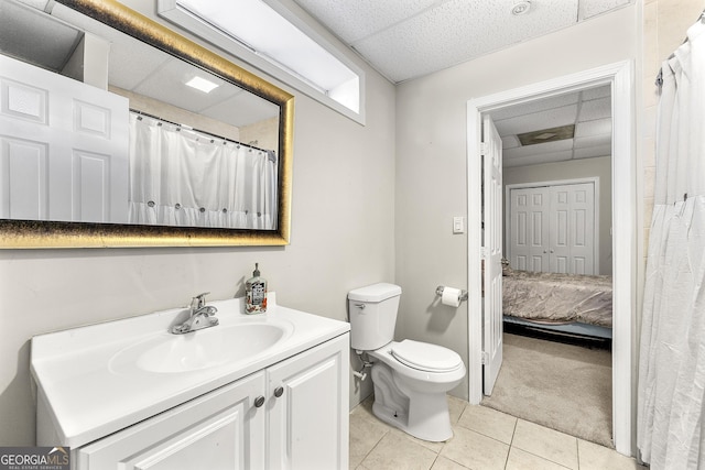 bathroom featuring tile patterned floors, vanity, toilet, and a paneled ceiling