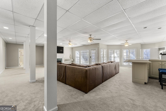 carpeted living room featuring ceiling fan and a paneled ceiling