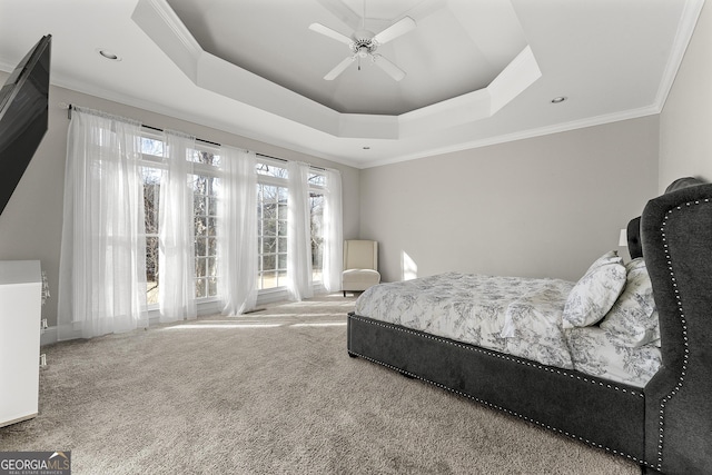 bedroom with a raised ceiling, ceiling fan, carpet floors, and ornamental molding