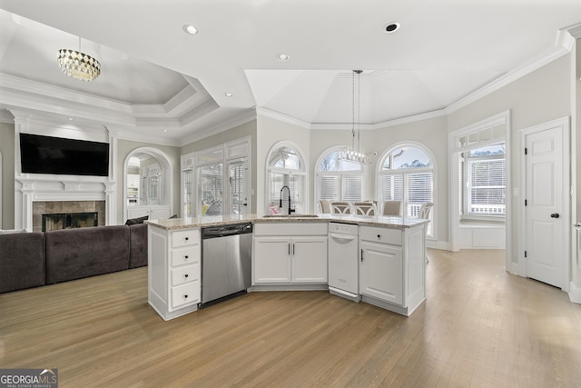 kitchen with white cabinetry, a tiled fireplace, dishwasher, light stone countertops, and pendant lighting