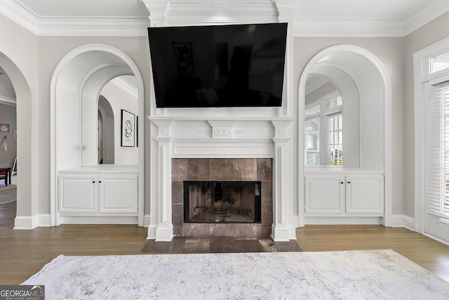 unfurnished living room with crown molding, a healthy amount of sunlight, and a tiled fireplace