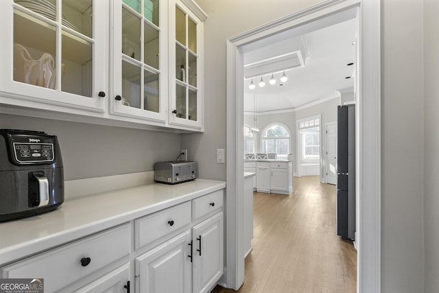 bar featuring white cabinetry, black refrigerator, dishwasher, crown molding, and light hardwood / wood-style flooring