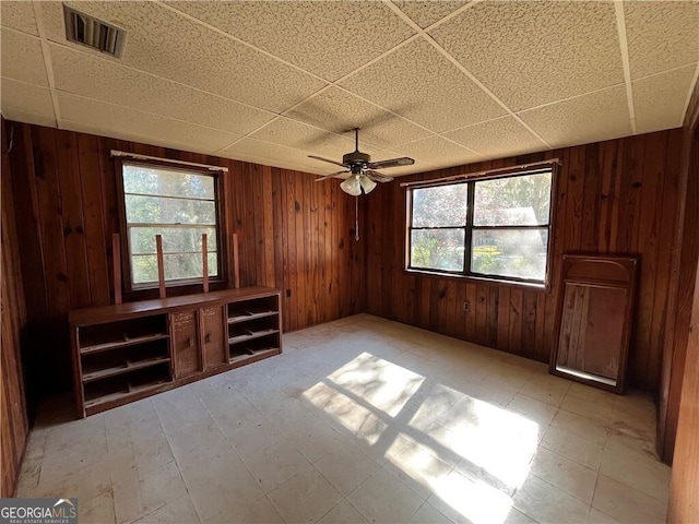 unfurnished living room featuring plenty of natural light and wood walls