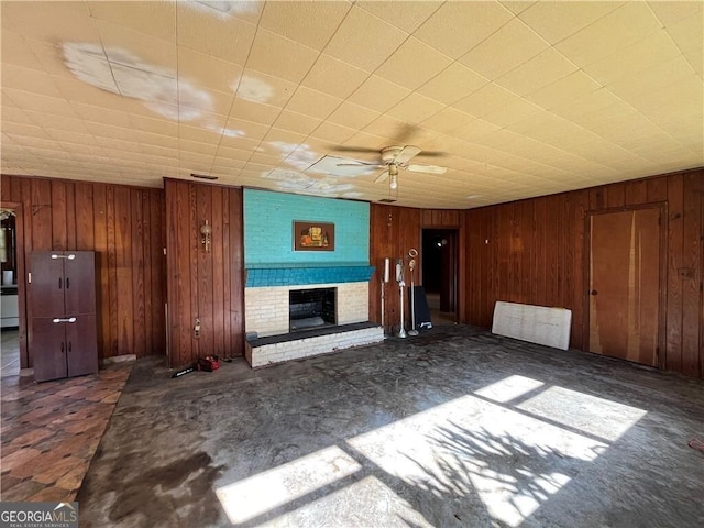 unfurnished living room featuring ceiling fan, a fireplace, and dark colored carpet