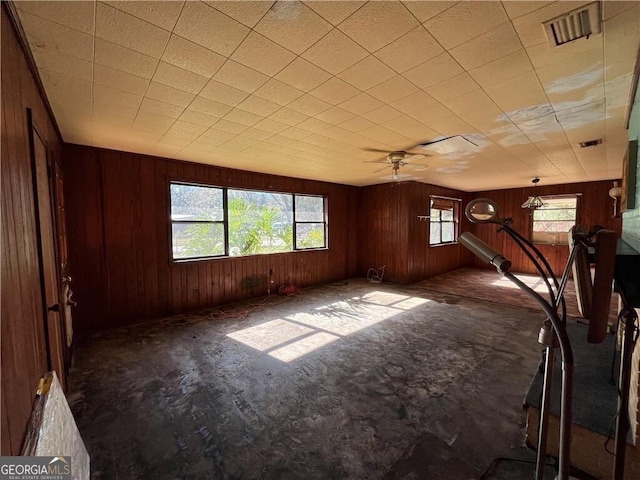 spare room featuring ceiling fan and wood walls