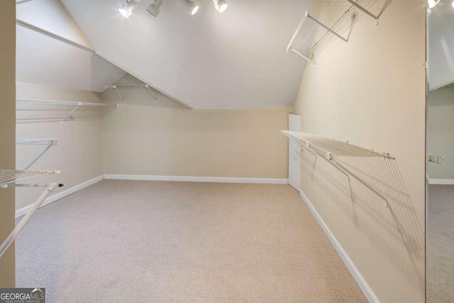 spacious closet with light carpet and vaulted ceiling