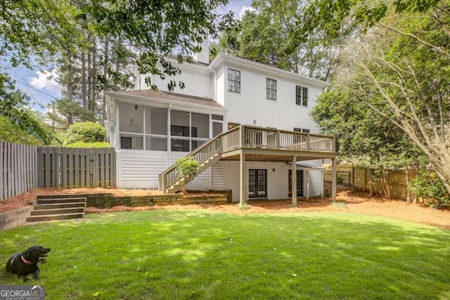 rear view of house with a sunroom, a deck, and a yard