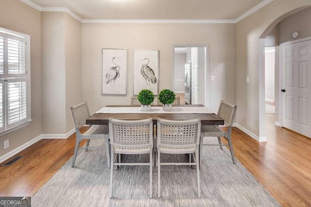 dining space featuring light hardwood / wood-style floors and crown molding