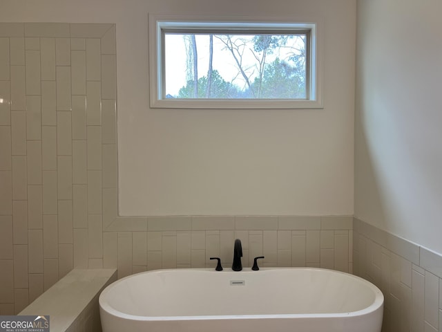 full bathroom with a soaking tub and tile walls