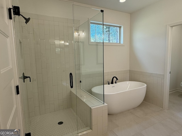 full bath with a freestanding bath, a stall shower, tile walls, and tile patterned floors