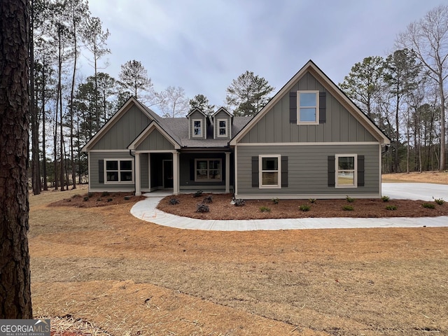 craftsman inspired home with board and batten siding, covered porch, and roof with shingles