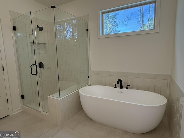 full bath with a soaking tub, a wainscoted wall, a stall shower, and tile walls