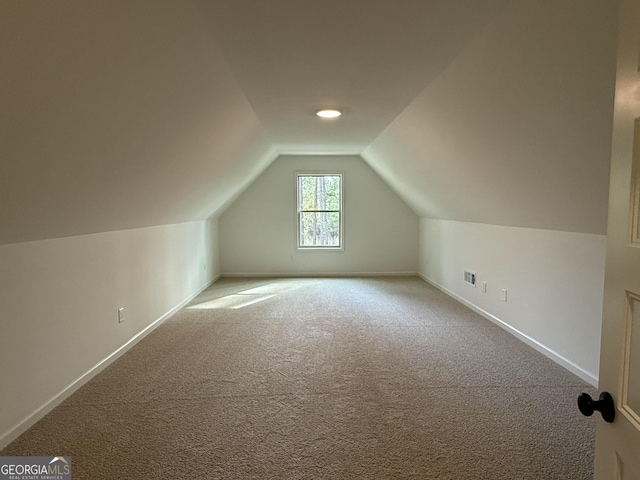 additional living space with carpet flooring, baseboards, and vaulted ceiling