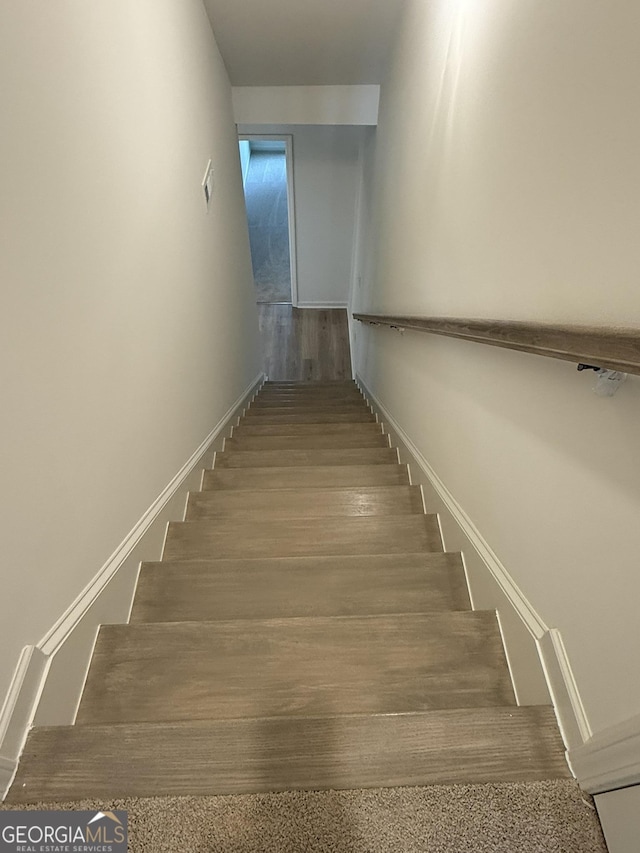 staircase with baseboards and wood finished floors