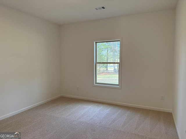 empty room with light colored carpet, visible vents, and baseboards