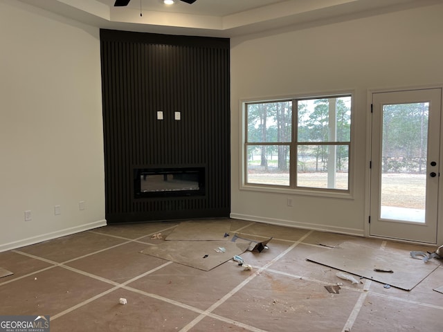 unfurnished living room featuring a ceiling fan and baseboards