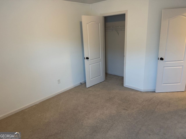 unfurnished bedroom with light carpet and a closet