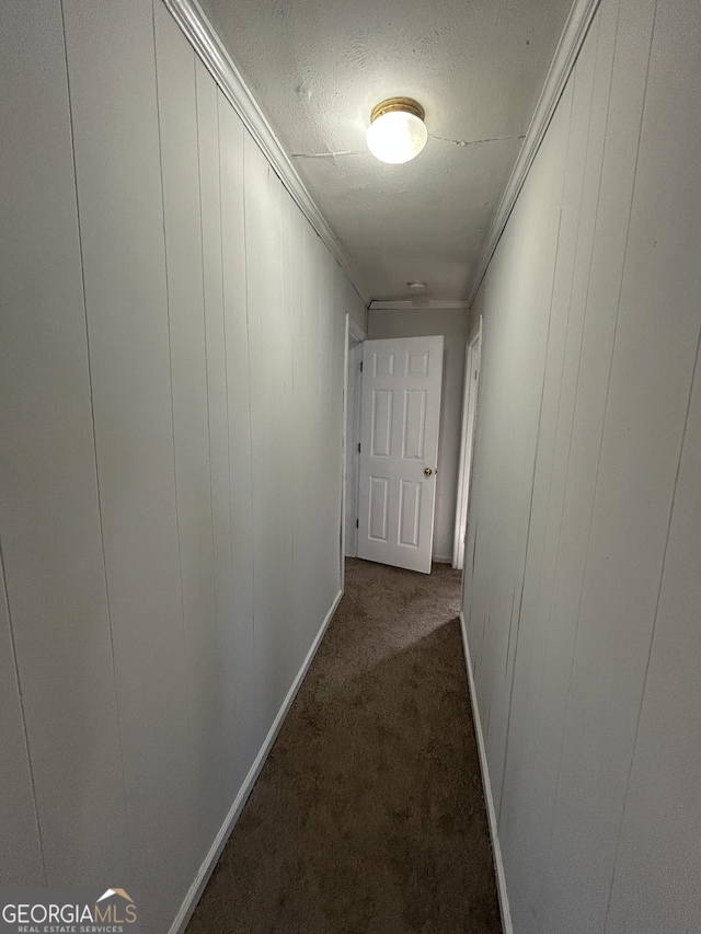 hall featuring ornamental molding, dark colored carpet, and a textured ceiling