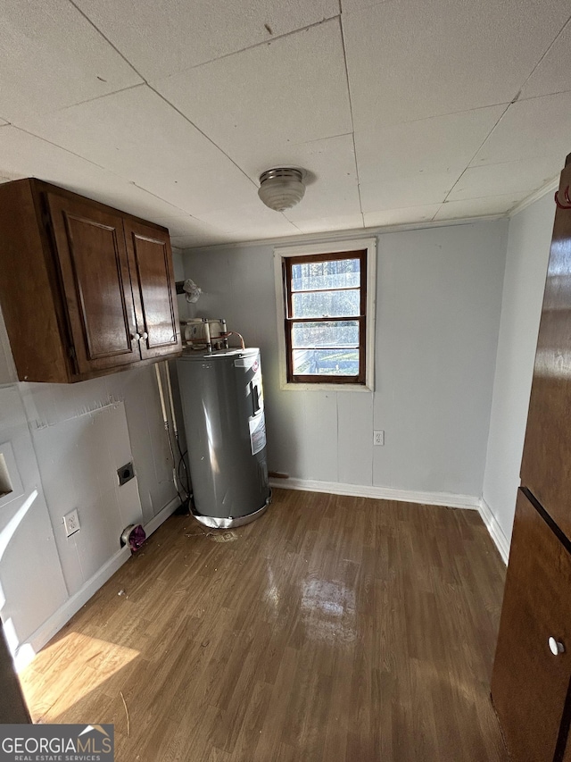 laundry area with electric water heater, dark wood-type flooring, cabinet space, and baseboards