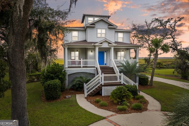 view of front of home featuring covered porch and a yard