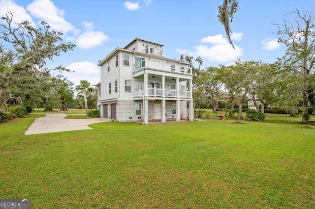 rear view of property with a yard, a balcony, a garage, and ceiling fan