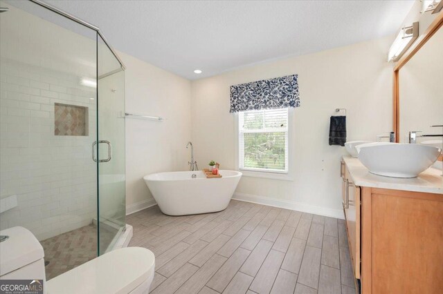 full bathroom with plus walk in shower, vanity, and toilet