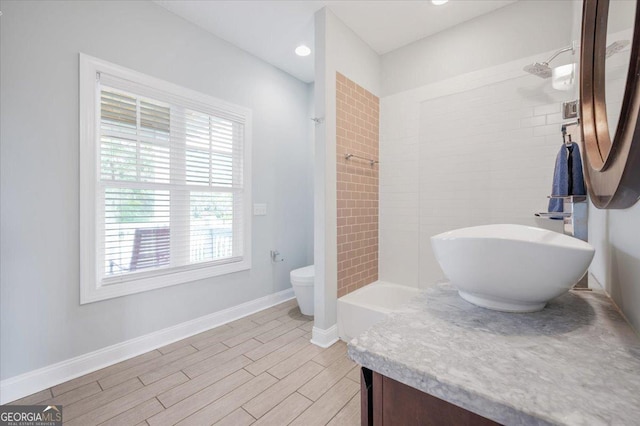 full bathroom with tiled shower / bath, vanity, and toilet