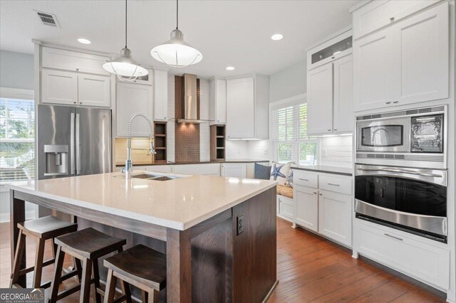 kitchen featuring sink, tasteful backsplash, a kitchen island with sink, white cabinets, and appliances with stainless steel finishes