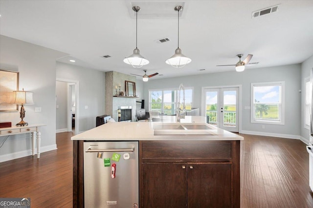 kitchen with ceiling fan, dishwasher, french doors, sink, and a kitchen island with sink