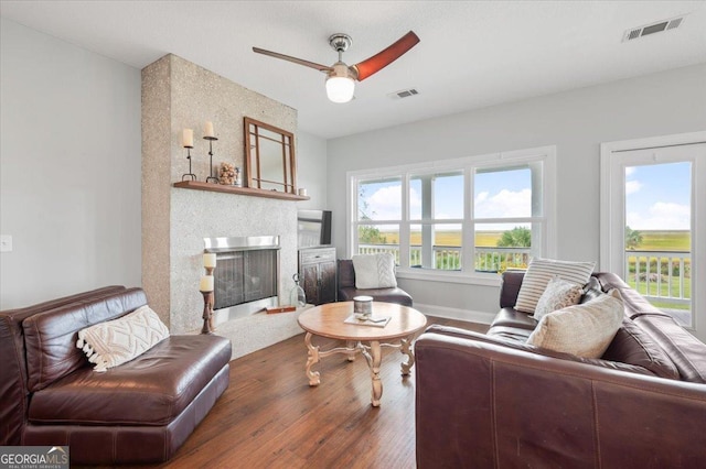 living room featuring ceiling fan, a fireplace, and dark hardwood / wood-style floors