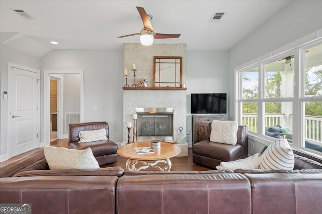 living room featuring ceiling fan, wood-type flooring, lofted ceiling, and a fireplace