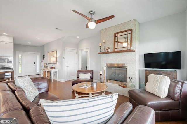 living room featuring hardwood / wood-style floors, a large fireplace, and ceiling fan