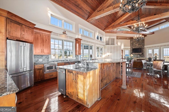 kitchen featuring stone counters, high vaulted ceiling, dark hardwood / wood-style floors, a kitchen island, and stainless steel appliances