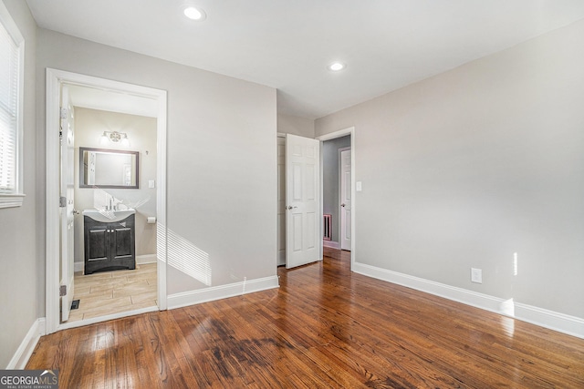 unfurnished bedroom featuring ensuite bath and hardwood / wood-style flooring