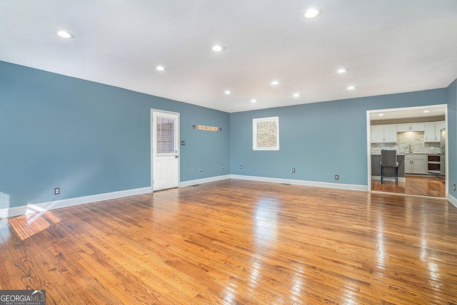 unfurnished living room with sink and light hardwood / wood-style floors