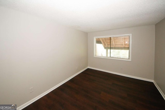 unfurnished room with dark hardwood / wood-style flooring and a textured ceiling