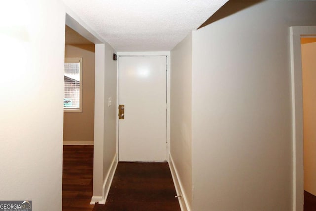 hallway with dark hardwood / wood-style flooring and a textured ceiling