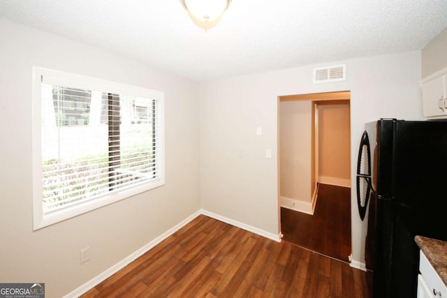 kitchen featuring black refrigerator, dark hardwood / wood-style flooring, and white cabinets