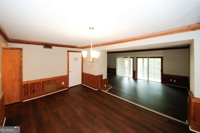 unfurnished dining area with a chandelier, wooden walls, dark hardwood / wood-style floors, and crown molding