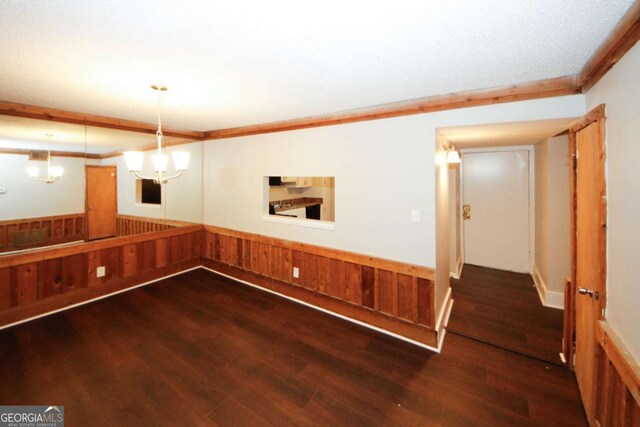 basement with wood-type flooring, ornamental molding, wooden walls, and an inviting chandelier