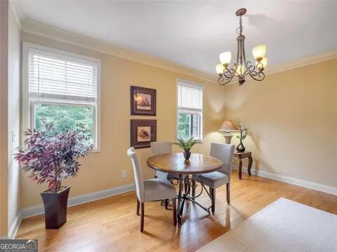 dining area featuring crown molding, hardwood / wood-style floors, a chandelier, and plenty of natural light