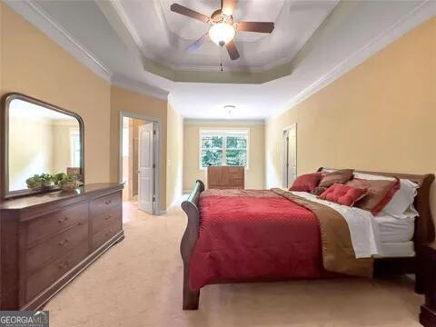 bedroom with ceiling fan, a raised ceiling, and crown molding