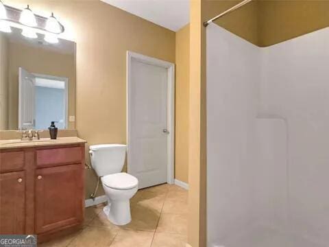 bathroom with tile patterned floors, a shower, vanity, and toilet