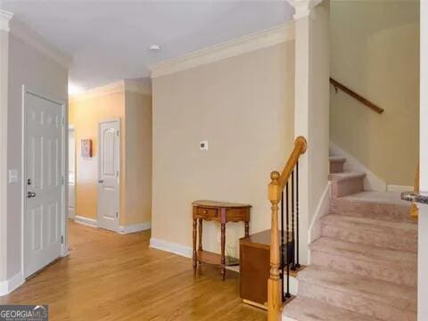 staircase with hardwood / wood-style floors and ornamental molding