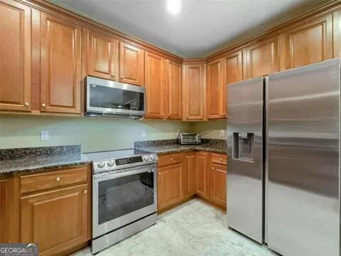 kitchen with dark stone countertops and stainless steel appliances